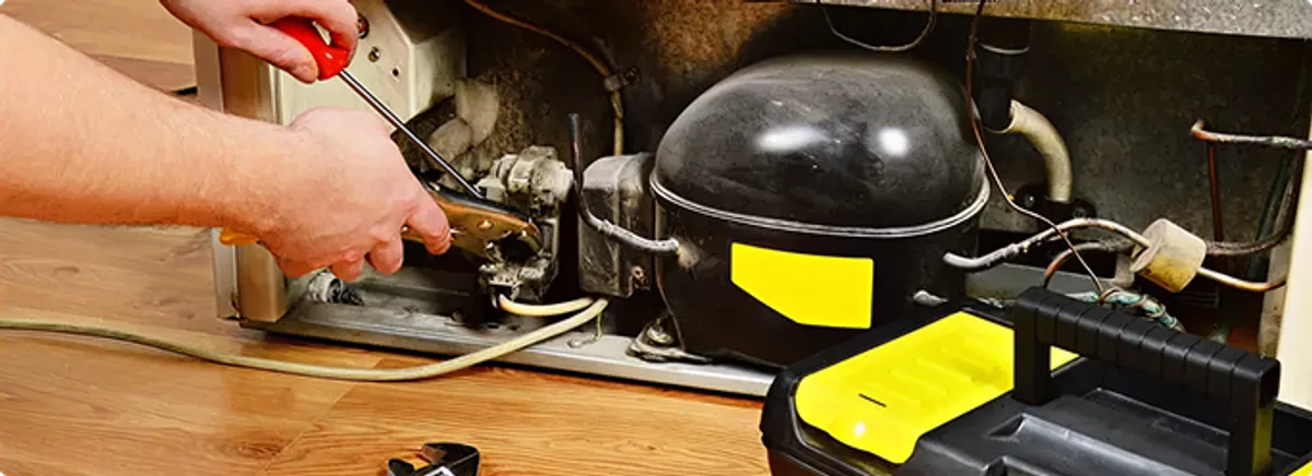 Refrigerator repair technician fixing the compressor and wiring in Decatur, GA