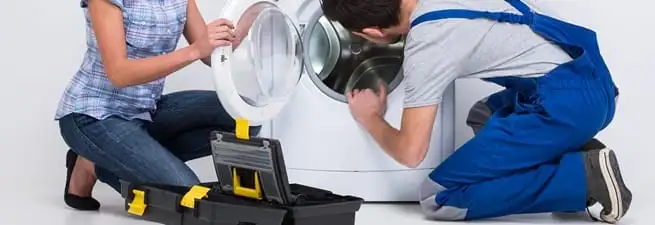 Washer repair technician inspecting a front-load washing machine with tools in Atlanta, GA