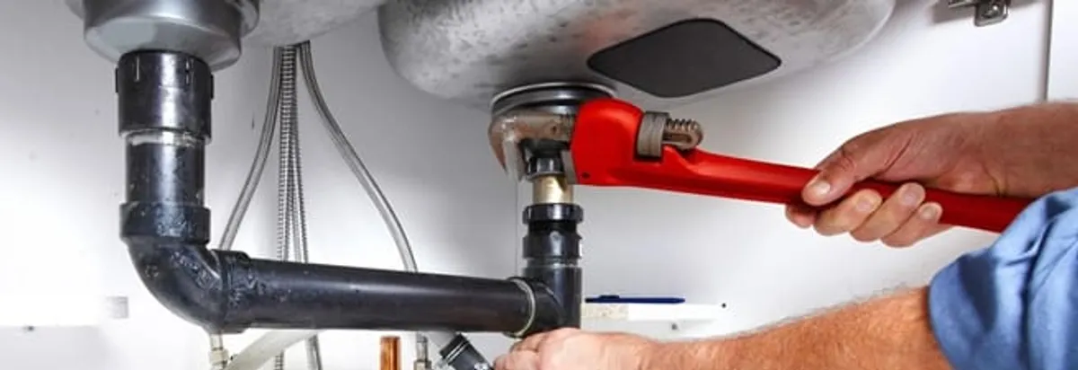 Garbage disposal repair technician tightening the sink drain and disposal connection in Atlanta, GA