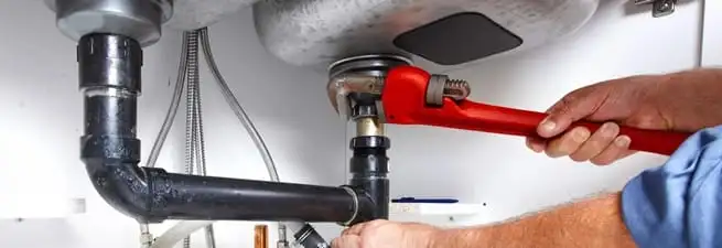 Garbage disposal repair technician tightening the sink drain and disposal connection in Atlanta, GA