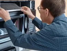 Appliance repair technician replacing a microwave vent filter in Atlanta, GA