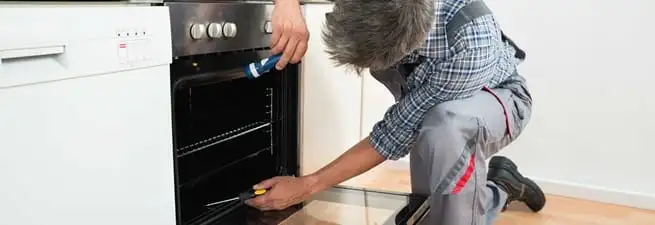 Oven repair technician inspecting and servicing an electric oven in Atlanta, GA