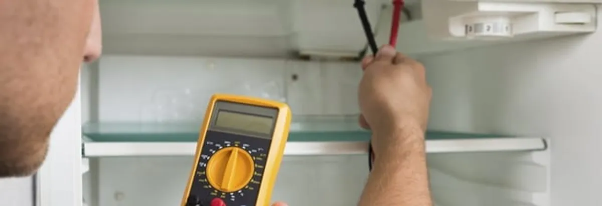 Refrigerator repair technician testing electrical components with a multimeter in Atlanta, GA