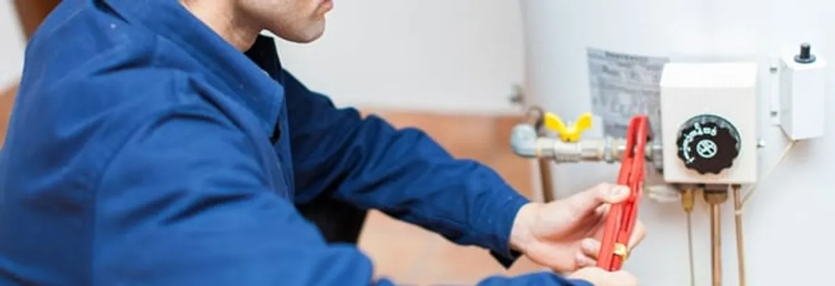 Water heater repair technician adjusting the temperature control and gas valve in Atlanta, GA